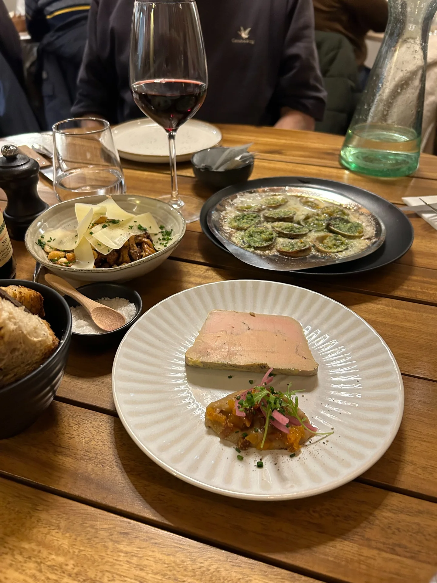 Plusieurs entrées servies sur une table en bois avec un verre de vin rouge chez Cocorico