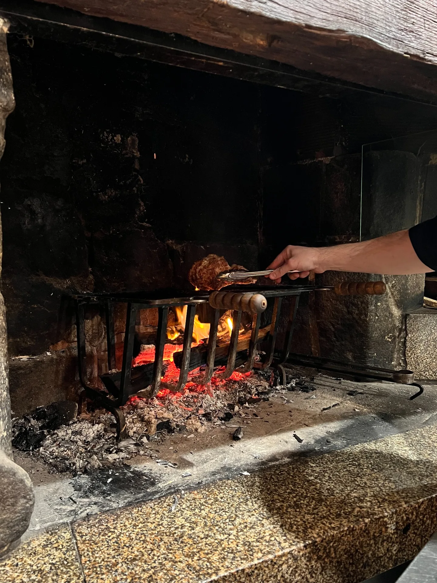 Cuisson d’une pièce de viande au-dessus des braises dans la cheminée de Cocorico