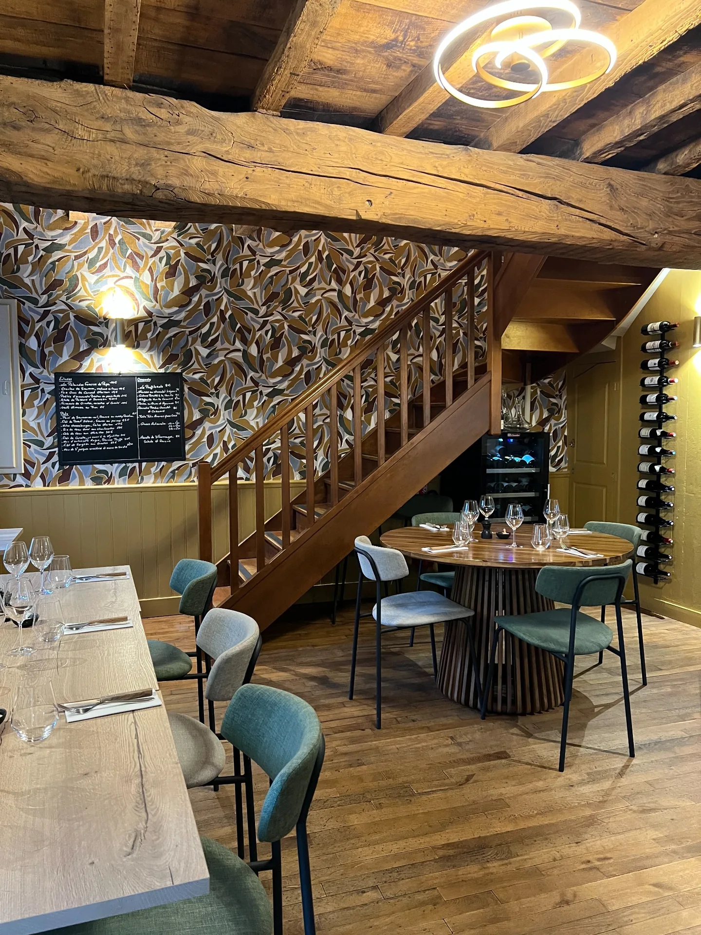 Salle de Cocorico avec son escalier en bois, ses tables et l’ardoise au mur