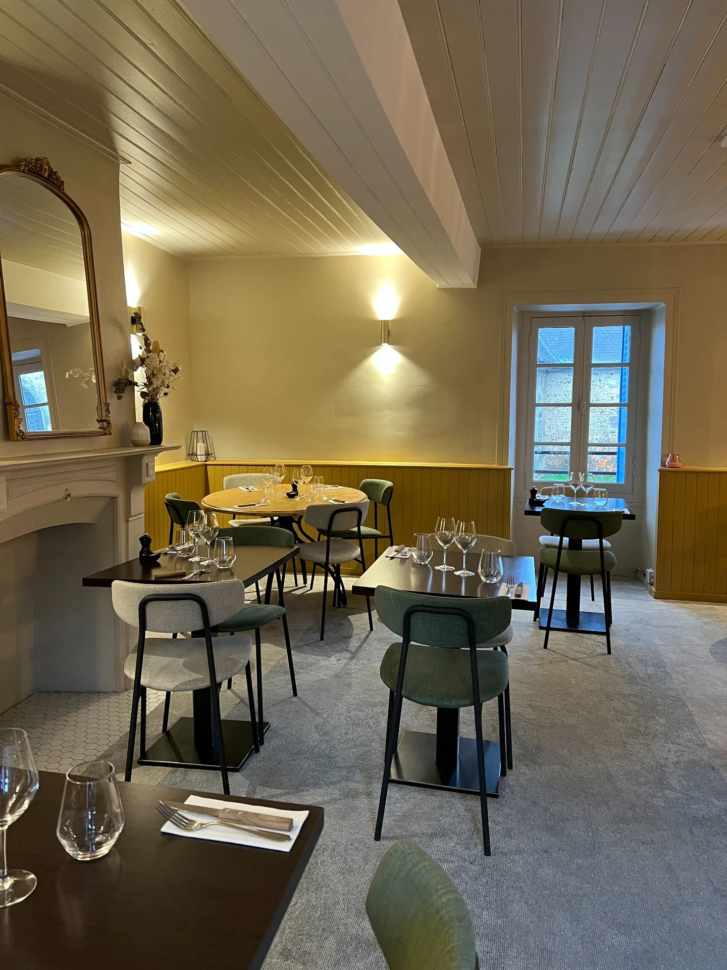 Salle de Cocorico avec ses tables dressées, sa cheminée et son grand miroir